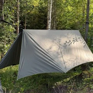 Olive winter tarp pitched over a hammock between birch trees