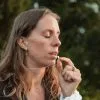 Woman breathing out slowly through the silver breathing necklace, eyes closed.