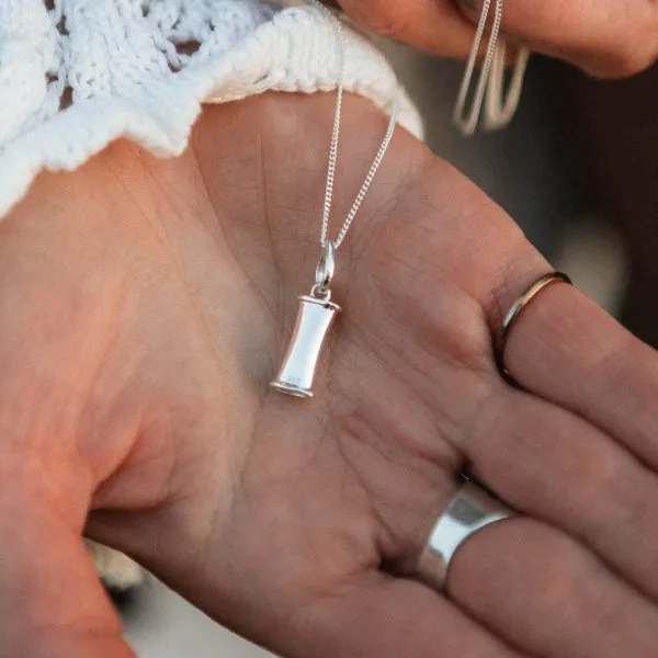 The silver breathing pendant resting in an open palm to show its size.