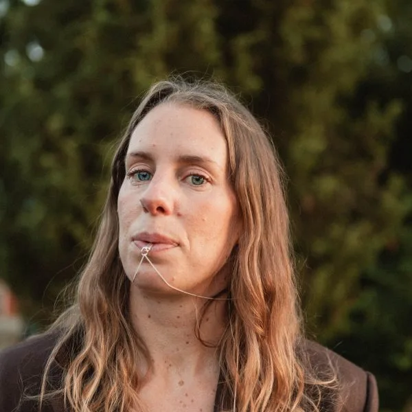 Woman wearing the breathing necklace with the pendant resting at her lips.